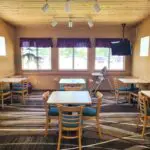 A dining room at the Parkfield Hotel with tables and chairs and a TV.