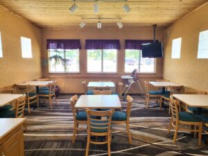A dining room at the Parkfield Hotel with tables and chairs and a TV.